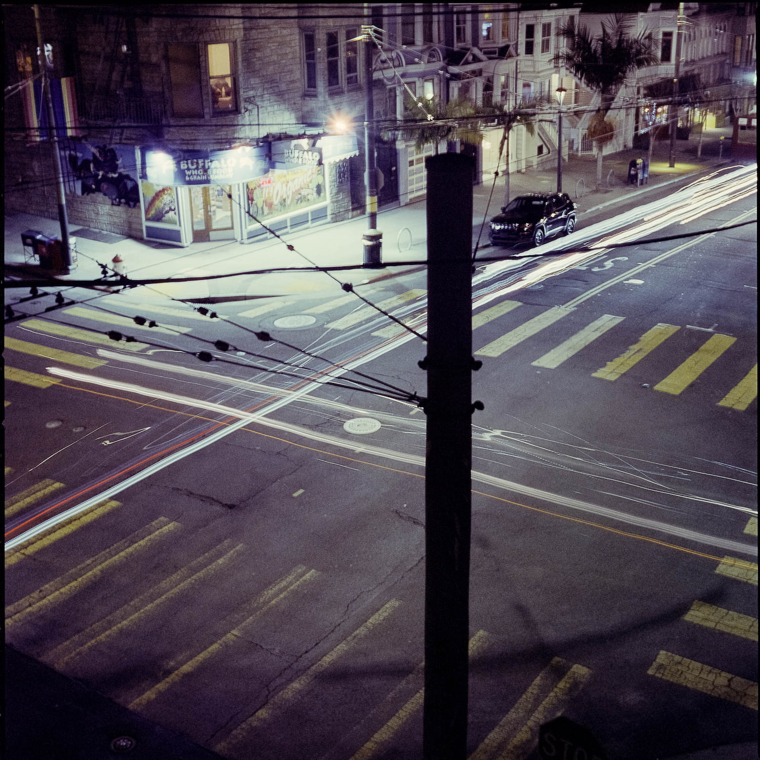 A long nighttime exposure with car headlights trailing through an intersection.